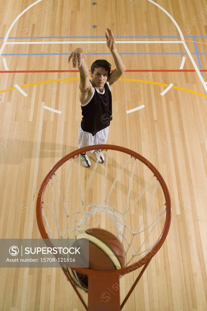 A young man shooting a basketball into a basketball hoop