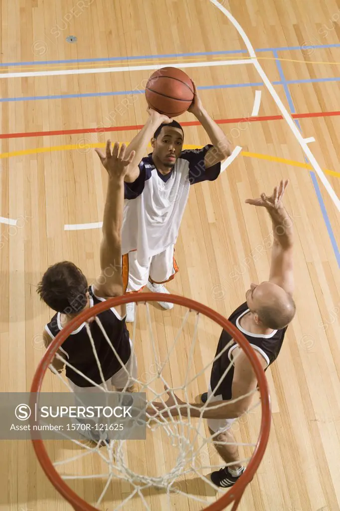 Three young men playing basketball