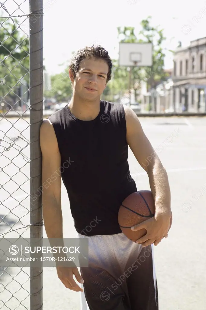 A Young man holding a basketball at an outdoor court