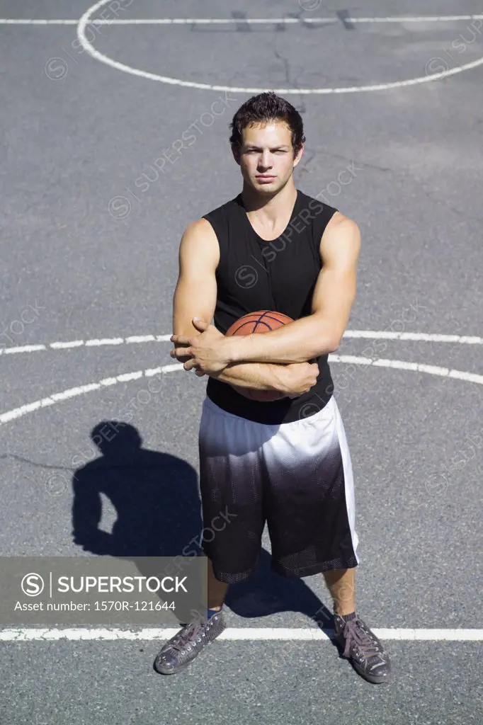 A young man standing on the free throw line at an outdoor basketball court