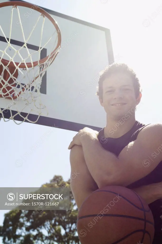 A young man standing near an outdoor basketball hoop