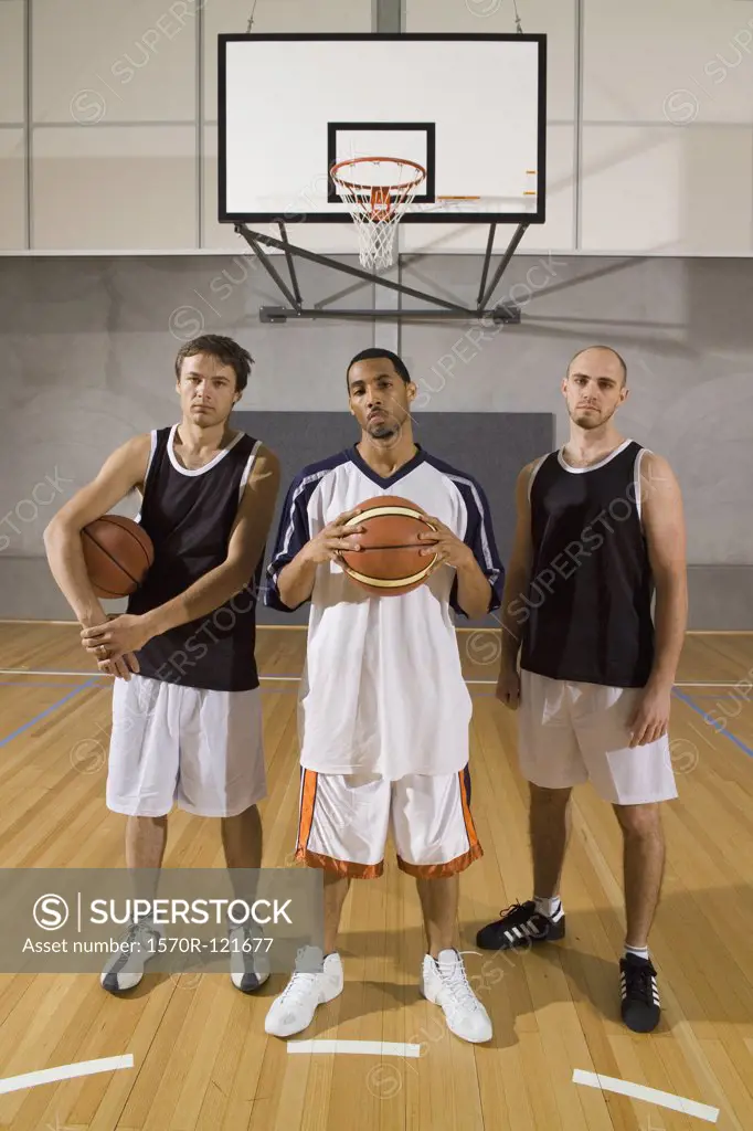 Three basketball players standing on a basketball court