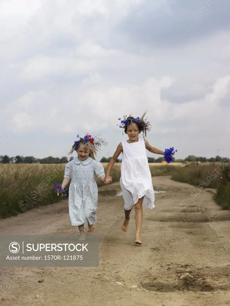 Two young girls running along a country road