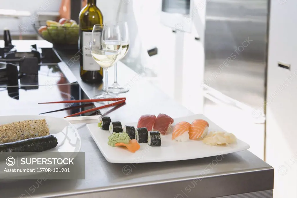 Sushi and white wine on a kitchen bench