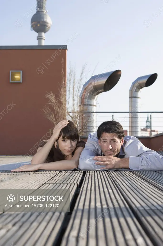 Portrait of a man and a woman lying together on a rooftop terrace