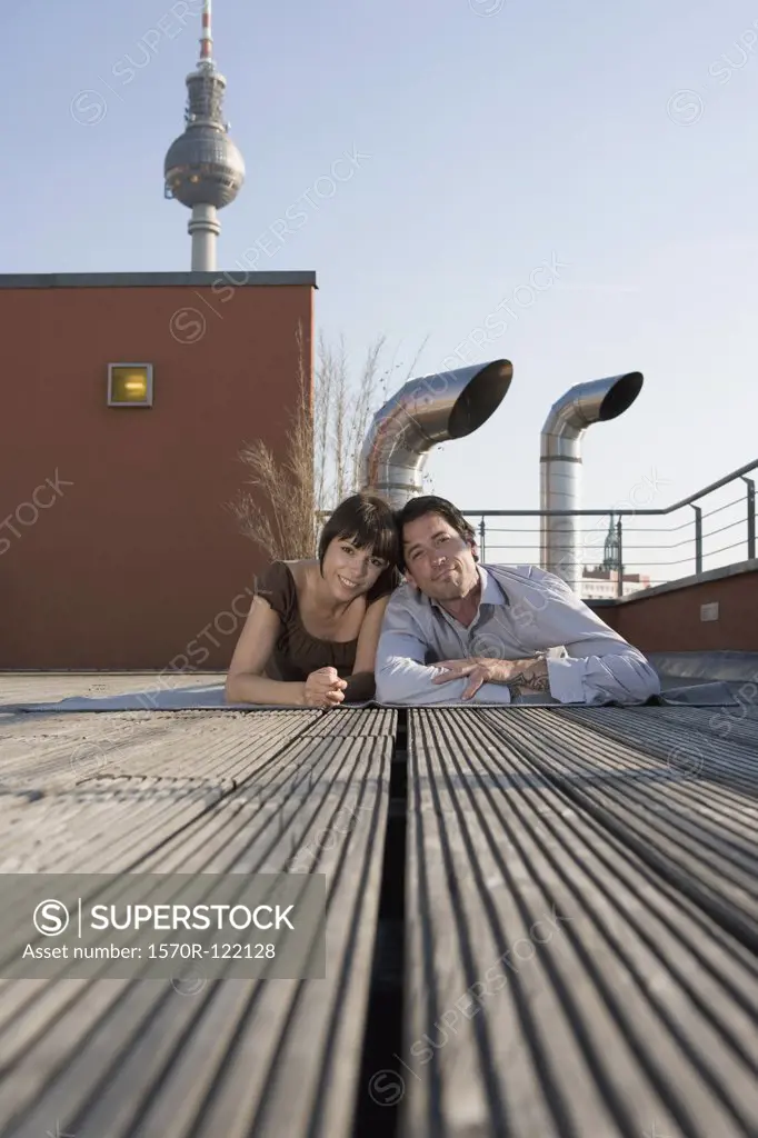 Portrait of a man and a woman lying together on a rooftop terrace