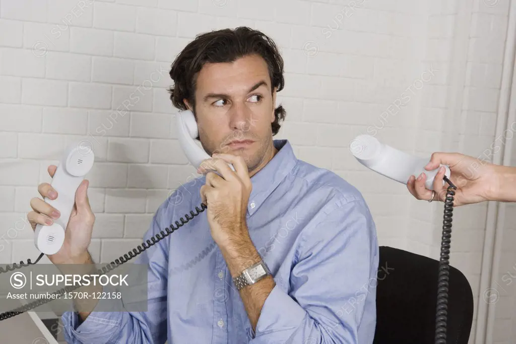 A businessman with three telephone receivers