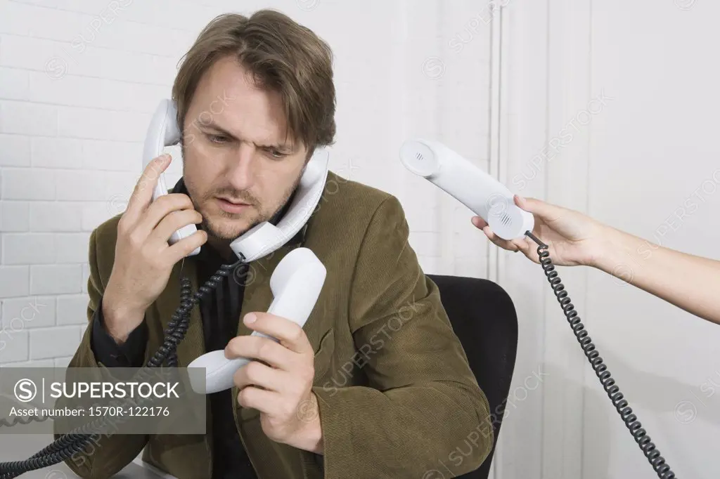 A businessman with four telephone receivers