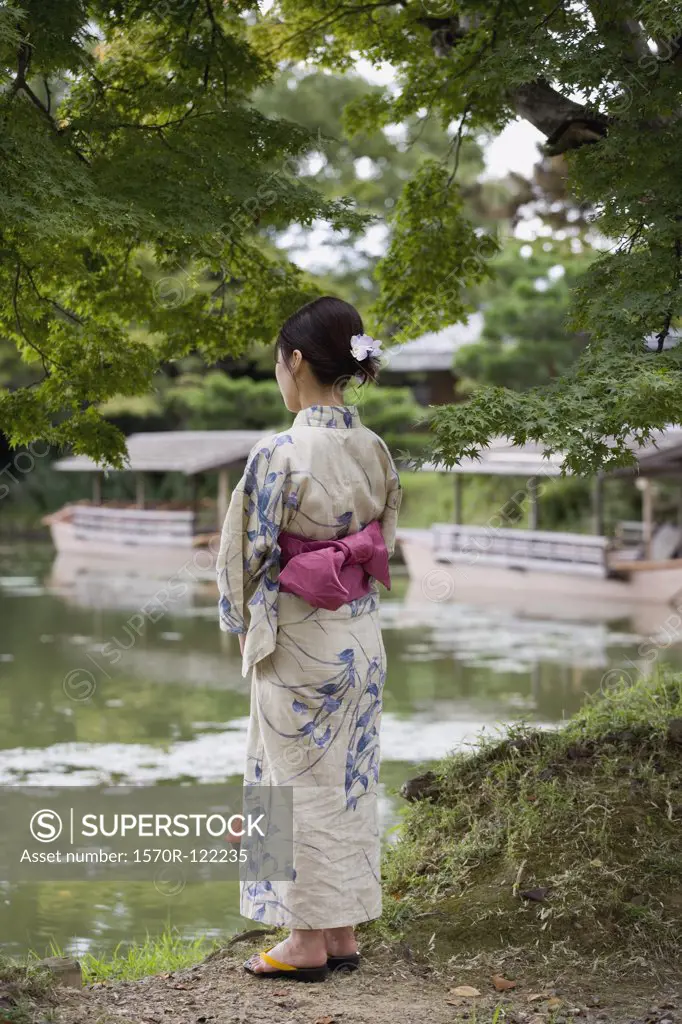 A woman wearing a kimono standing at the edge of a lake