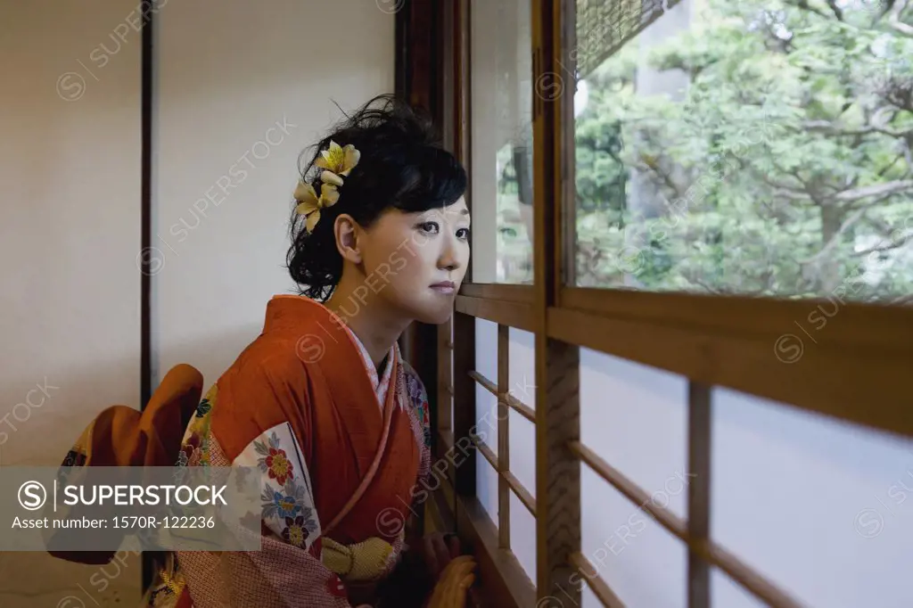 A woman wearing a kimono and looking out of a window