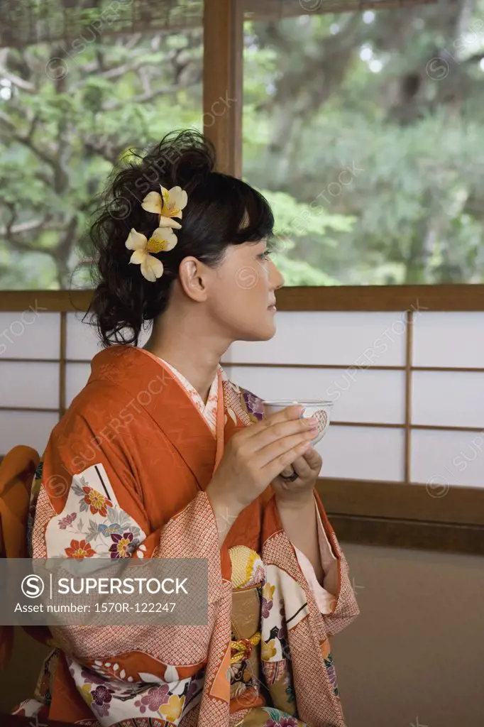 A woman wearing a kimono and drinking tea
