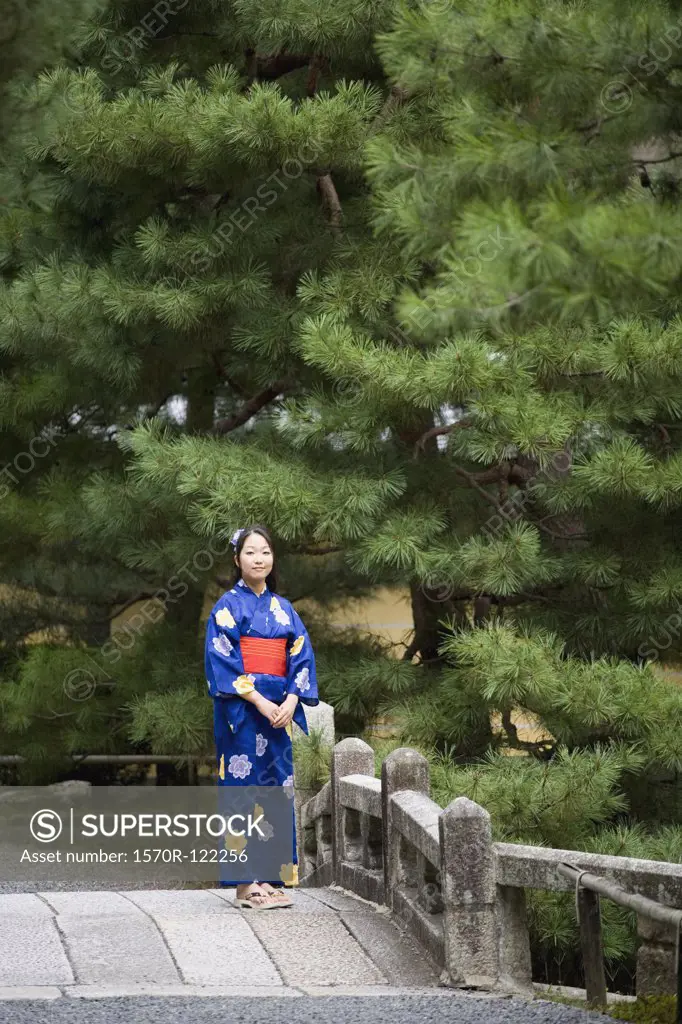 A woman wearing a kimono standing on a bridge