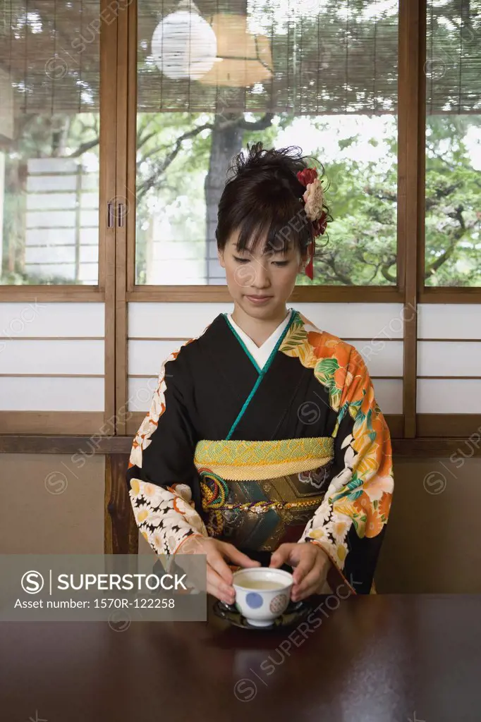 A woman wearing kimono and drinking tea