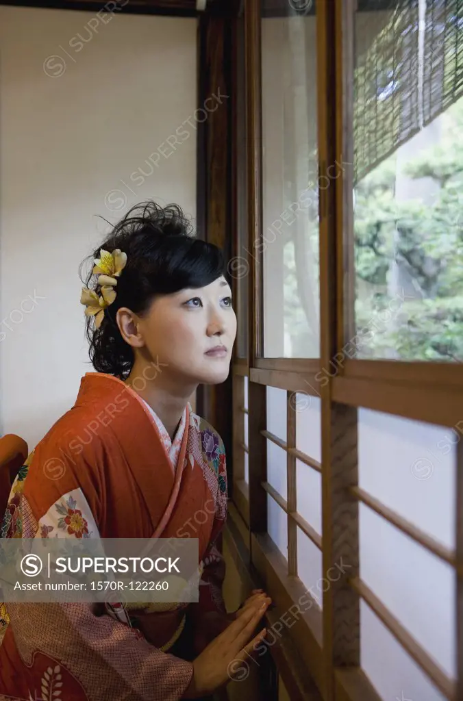 A woman wearing a kimono looking through a window