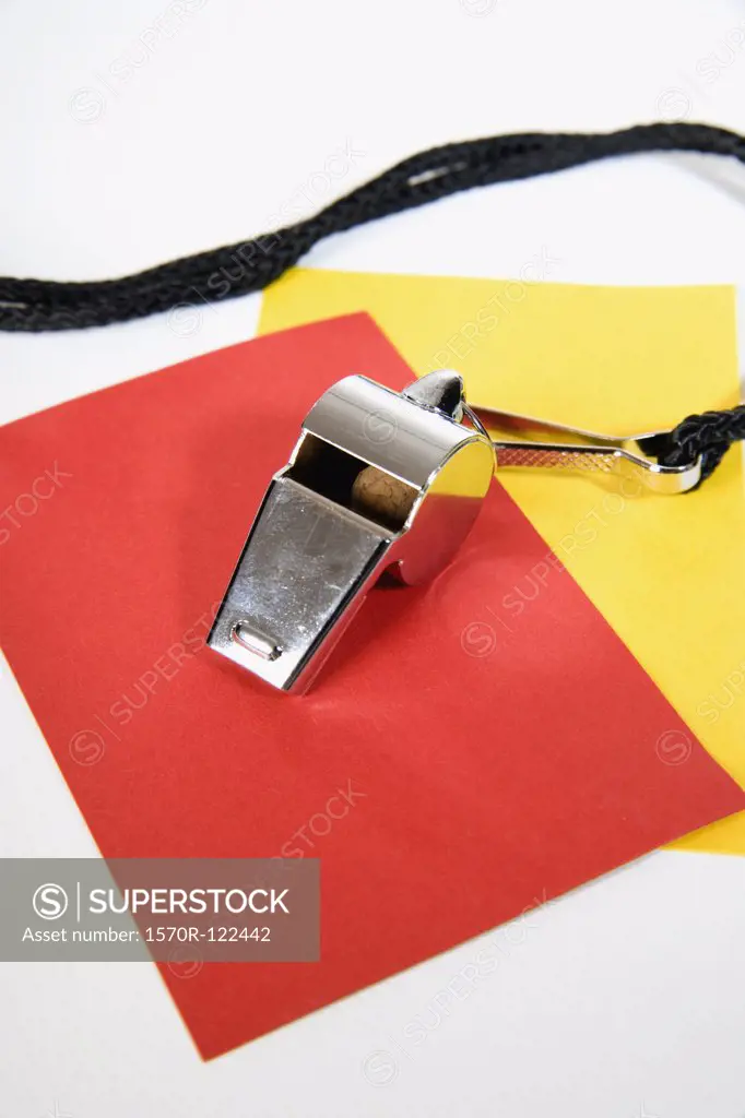 still life studio shot of a sports whistle, a red penalty card and a yellow warning card