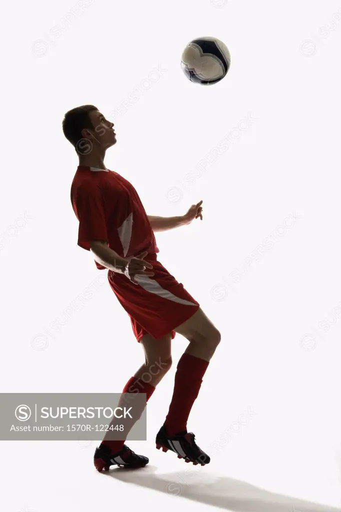 Studio shot of a soccer player bouncing a soccer ball on his chest
