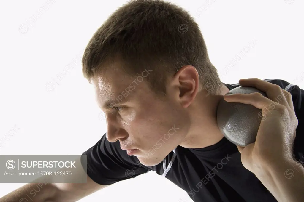 Studio shot of a male track and field athlete holding a shot put ball