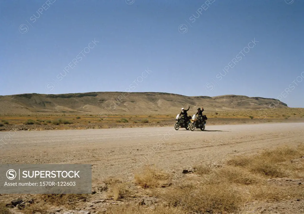 Two motorcyclists waving