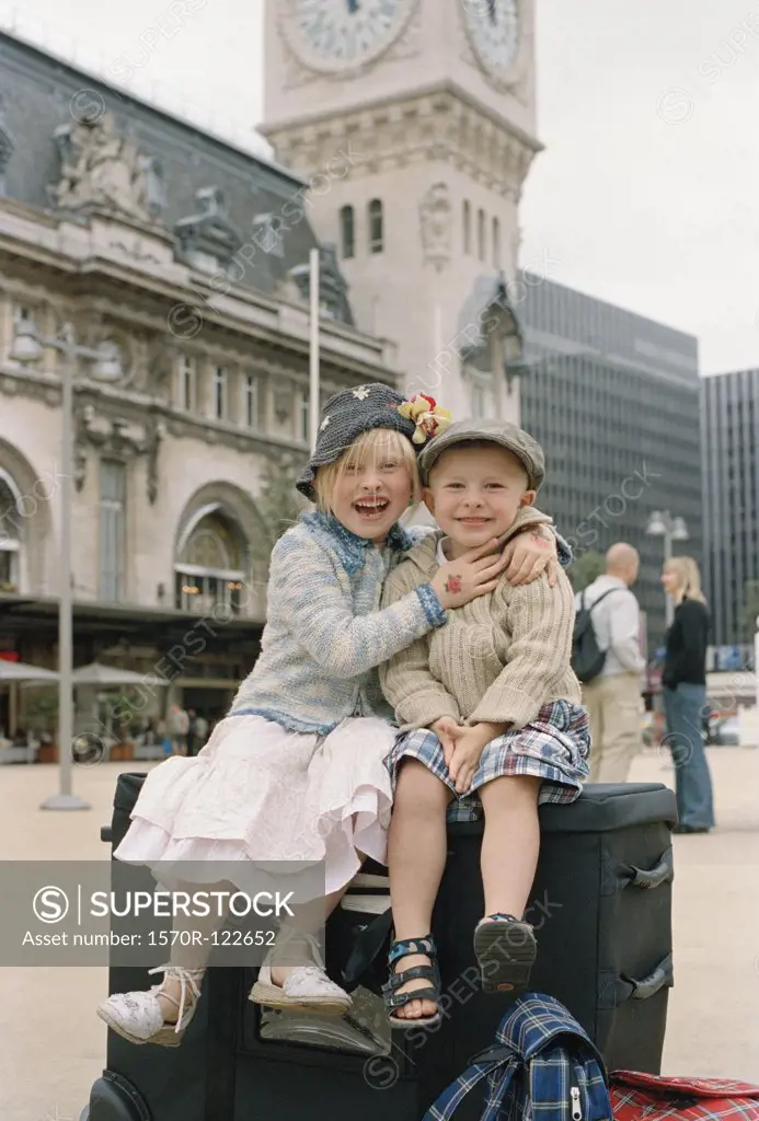 Two children sitting on luggage outside the Gare de Lyon, Paris