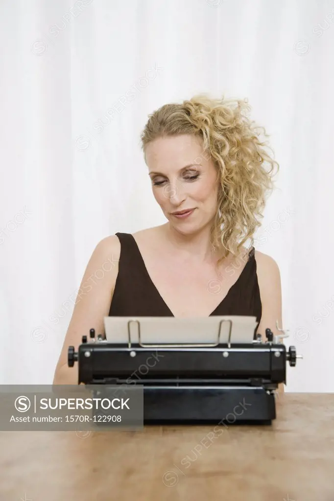 A mid adult woman looking down on a document in an old-fashioned typewriter