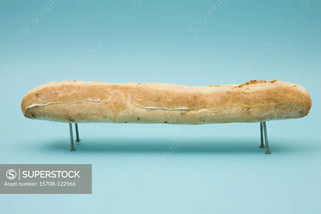 A baguette resting on four nails