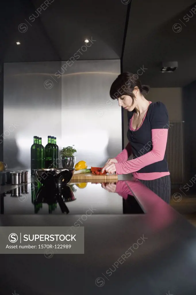 A mid adult woman slicing vegetables in a domestic kitchen