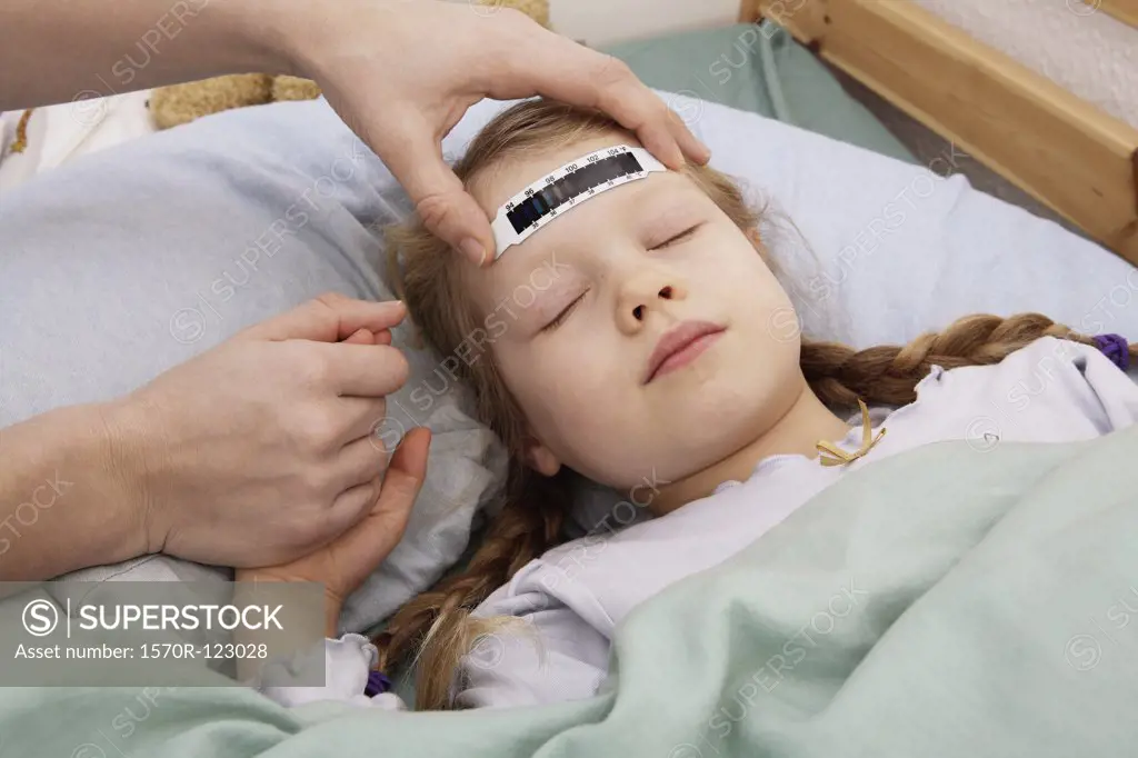 A young girl having her temperature taken with a forehead thermometer strip