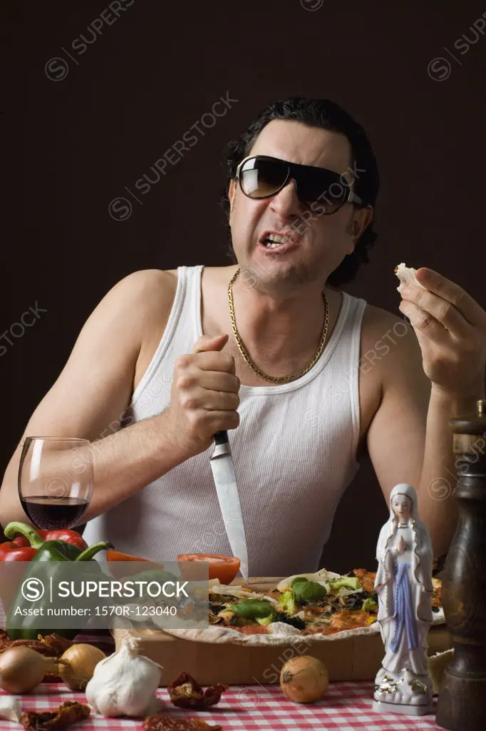 Stereotypical Italian Man sticking a knife in a cutting board aggressively and eating pizza