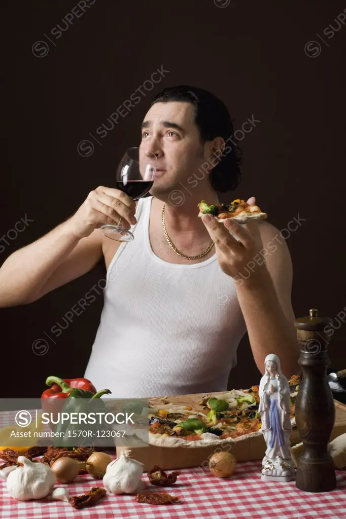 Stereotypical Italian man holding a wine glass and eating pizza