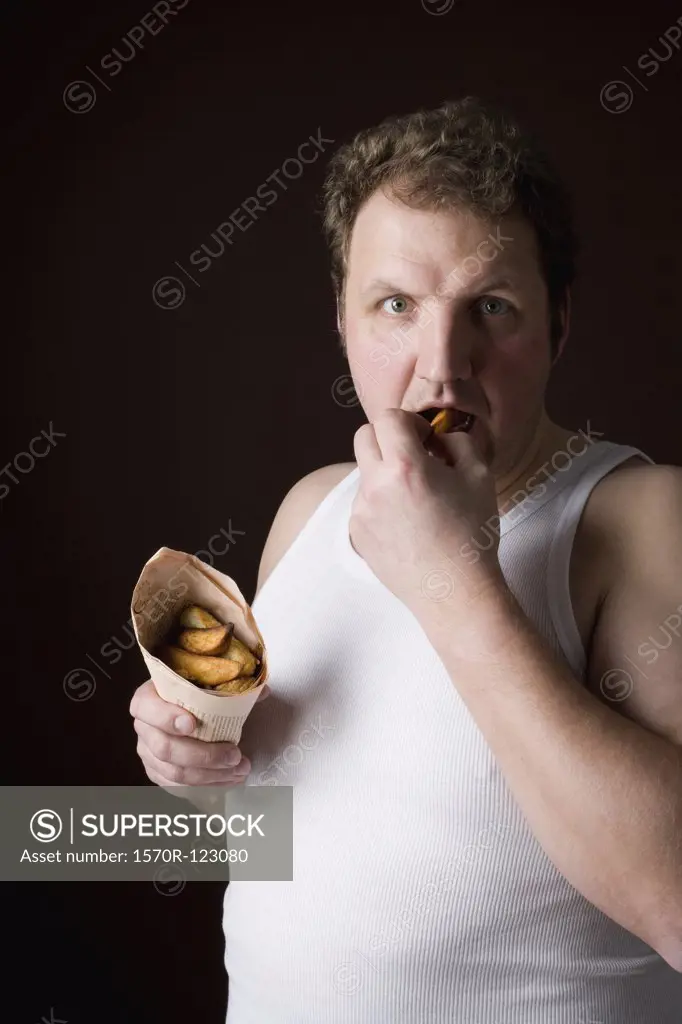 Stereotypical Englishman eating fish and chips in wrapped newspaper