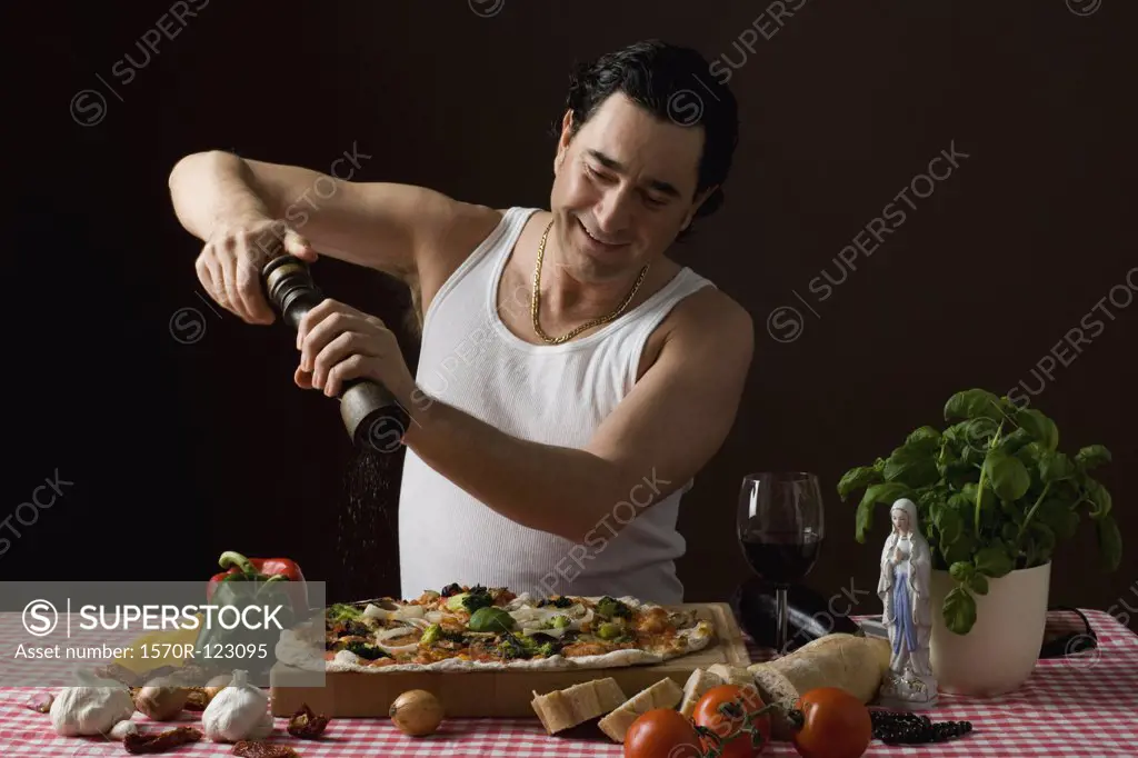 Stereotypical Italian man using a pepper mill on his pizza