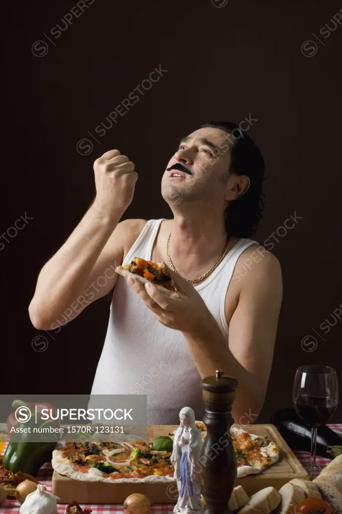 Stereotypical Italian man looking up and gesturing while eating pizza