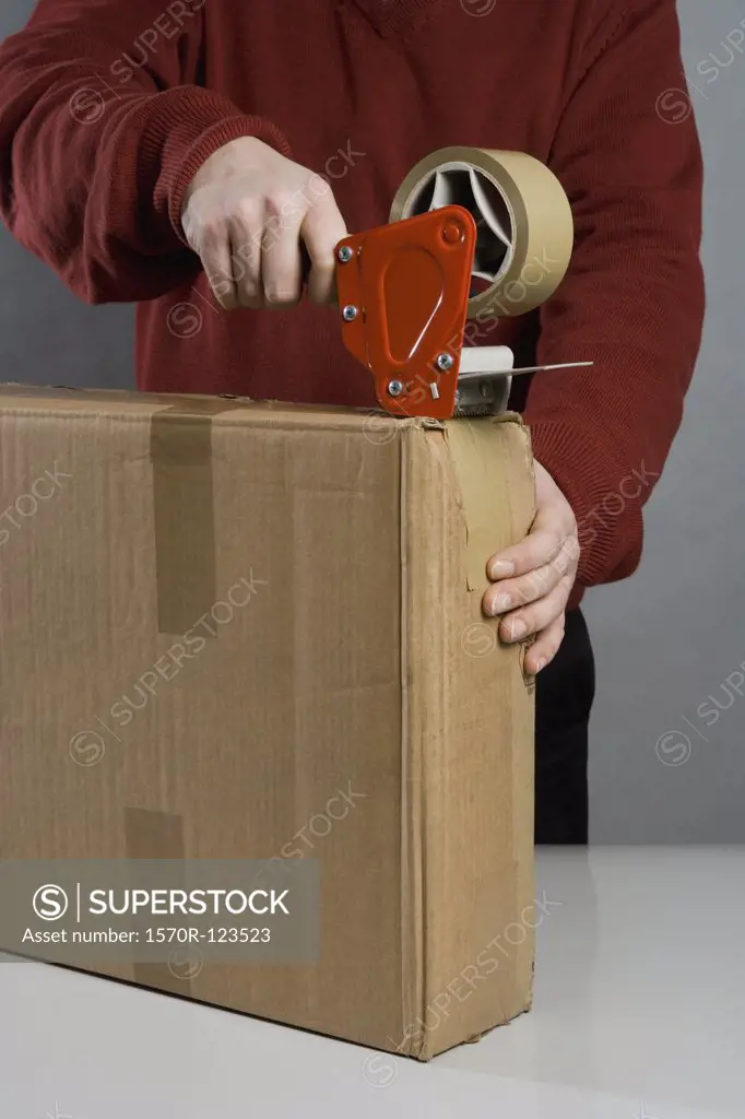 A man taping a cardboard box