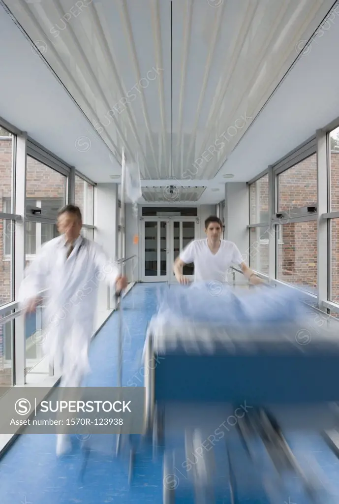 Two healthcare workers pushing a hospital bed along a corridor