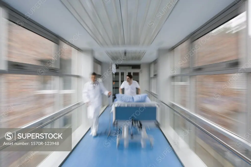 Two healthcare workers pushing a hospital bed along a corridor