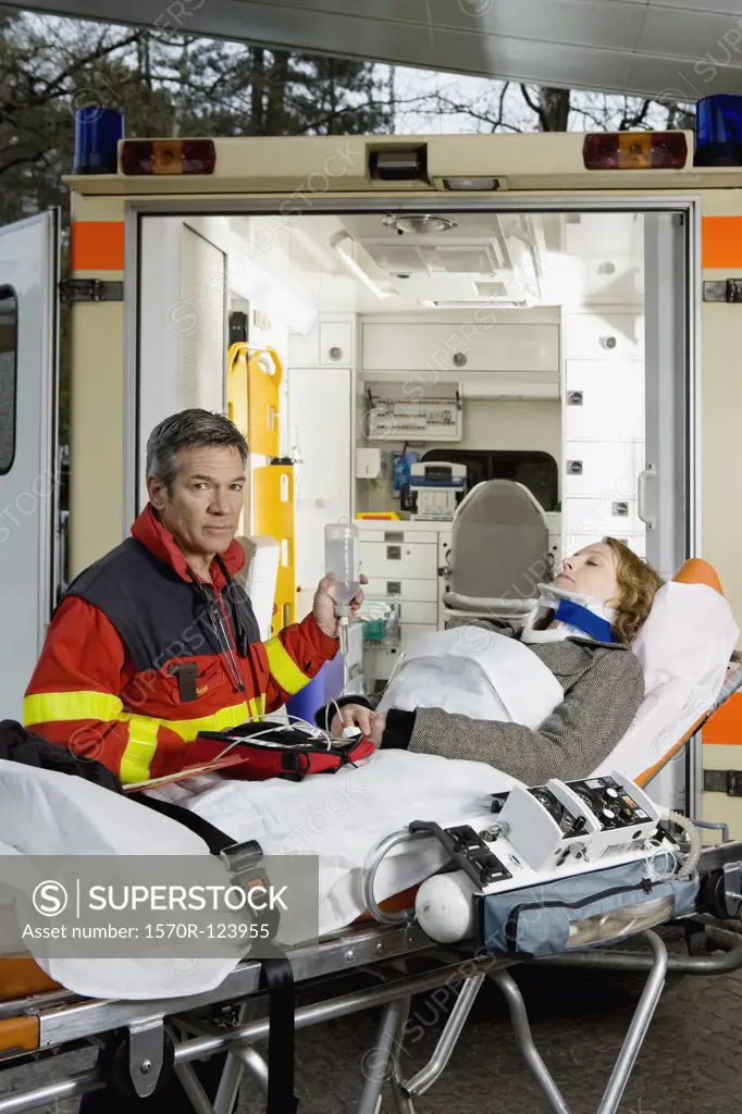 A paramedic assisting a woman in front of an ambulance
