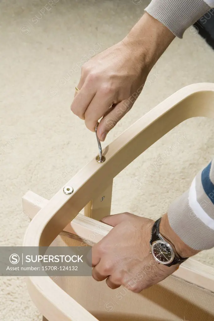 A man using an Allen wrench on a piece of furniture