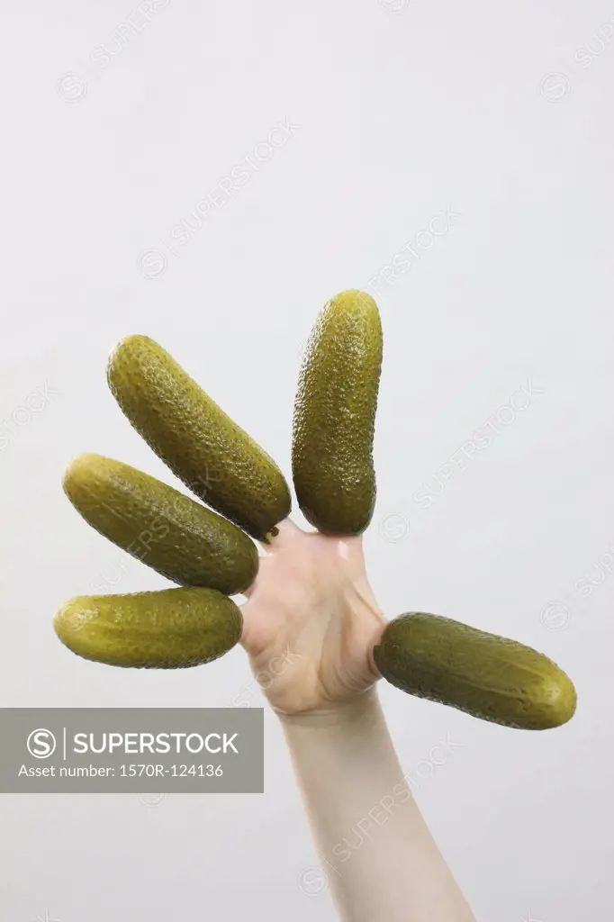 A hand with pickles on the fingers