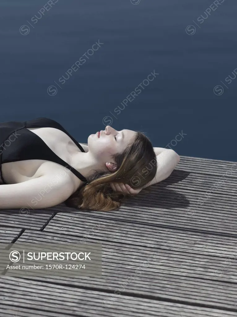 A woman in a swimsuit lying on a jetty
