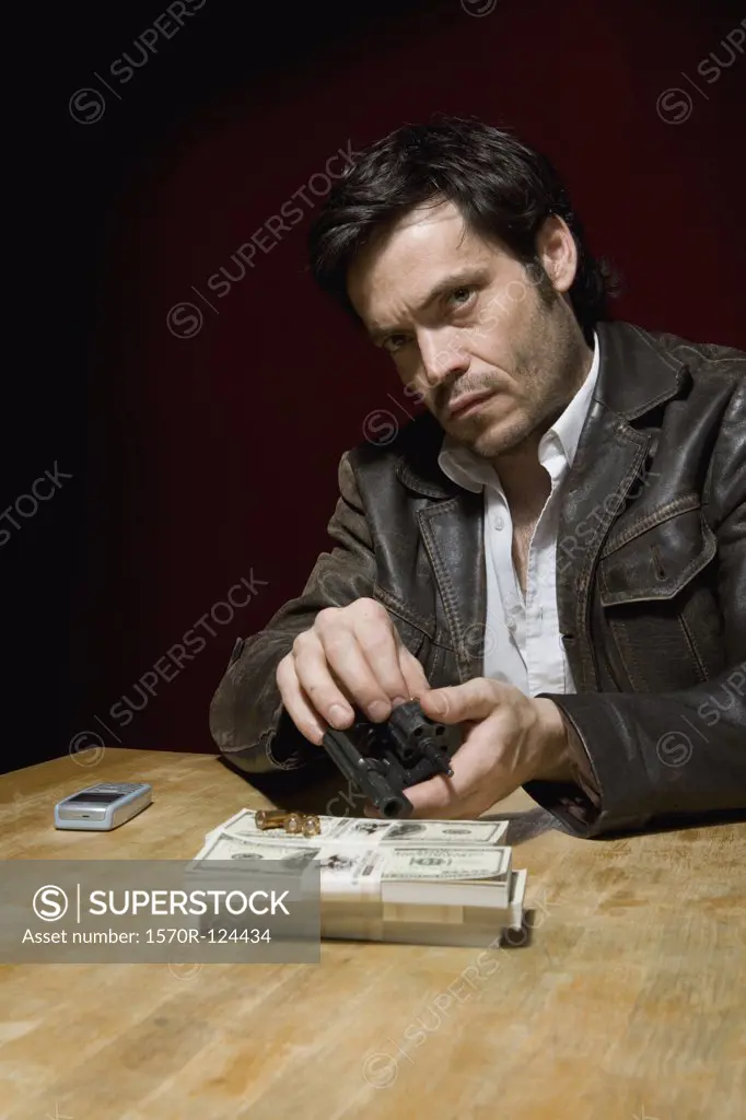 A man loading a gun with bullets next to several stacks of money