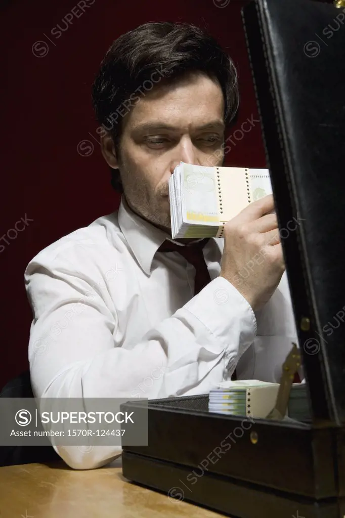 A man smelling a stack of money
