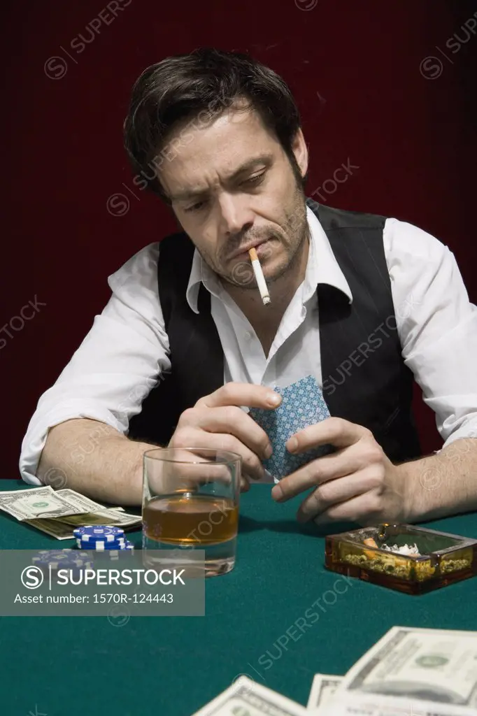 A man at a high stakes poker game looking at his hand of cards