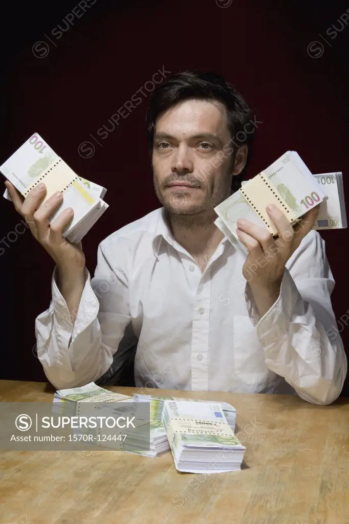 A man sitting at a table with bundles of hundrend euro banknotes