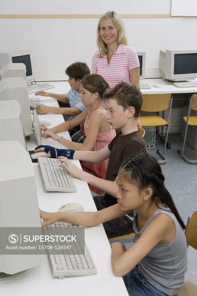 A teacher and four pre-adolescent children in a computer lab