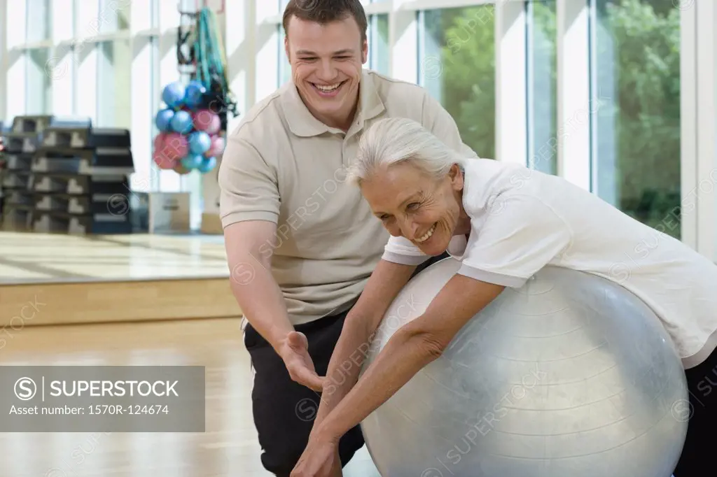 A senior woman on an exercise ball working with a trainer
