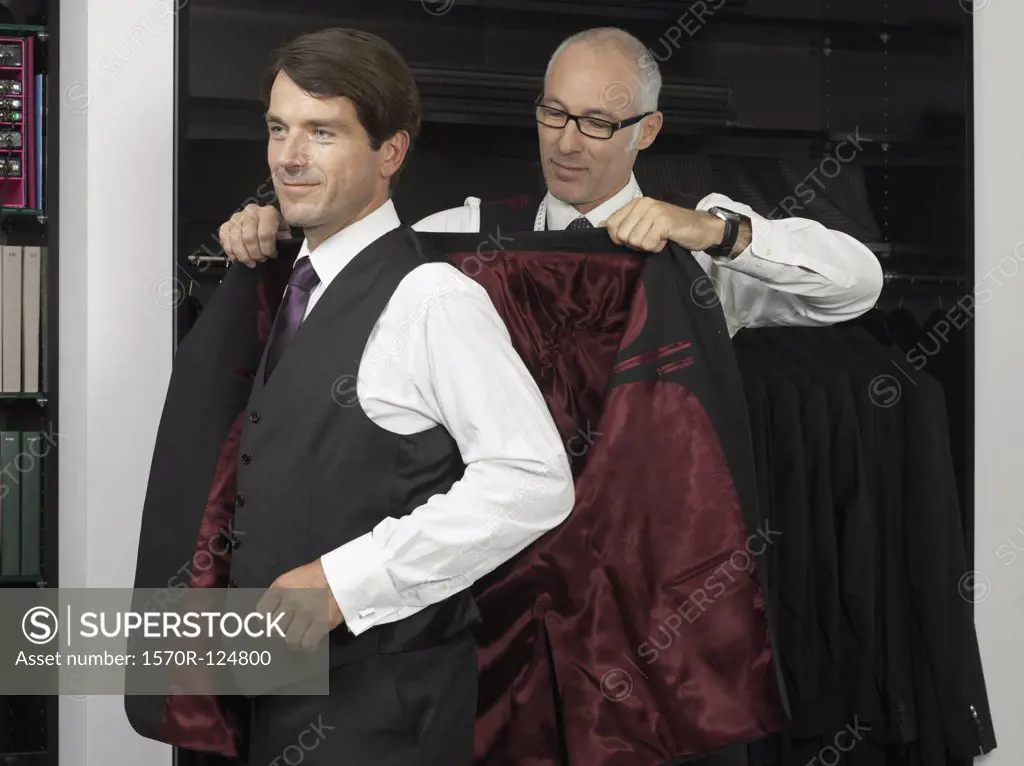 A tailor assisting a man trying on a suit