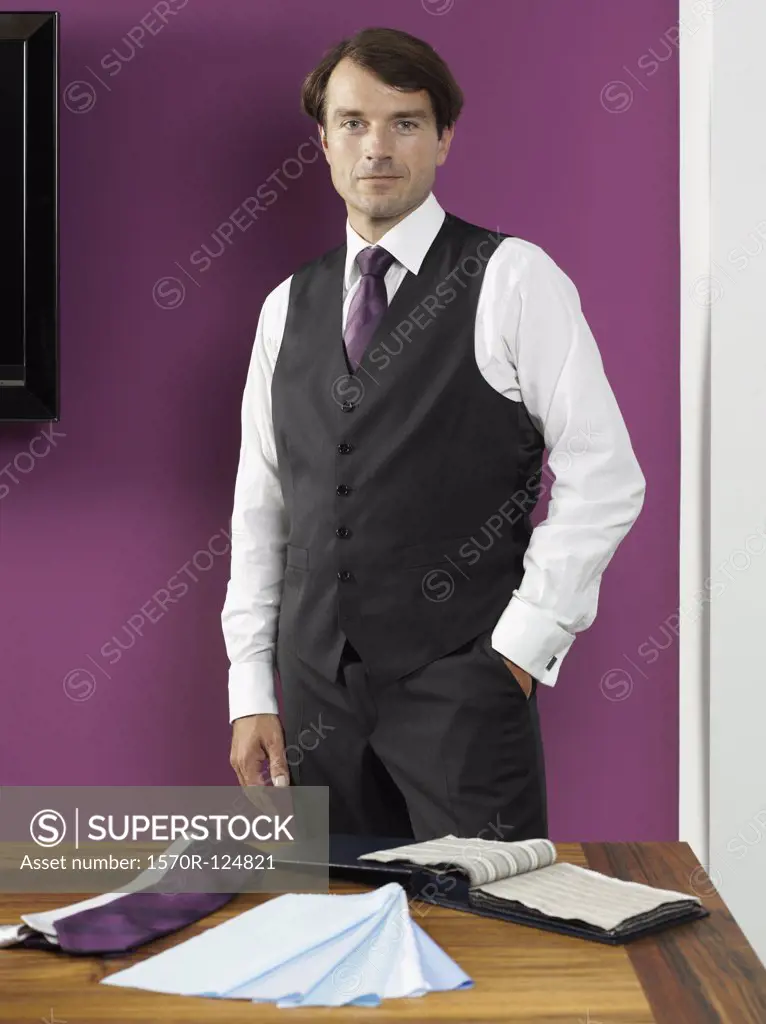 A tailor standing with fabric swatches