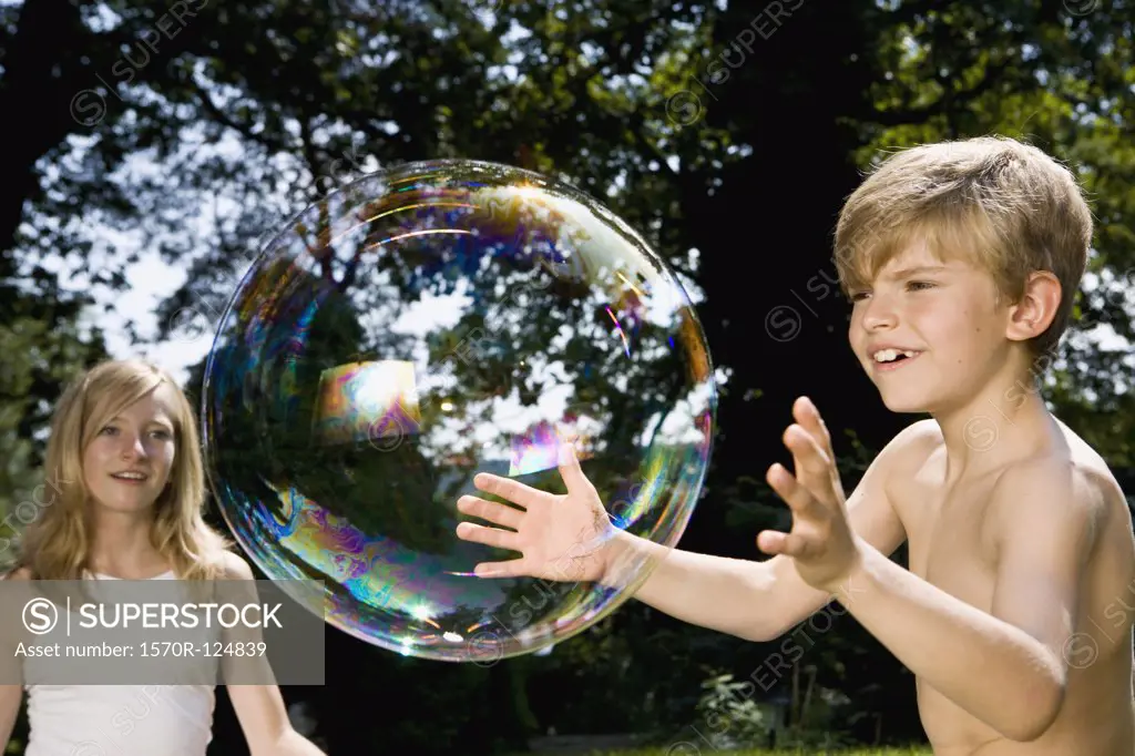 Two children trying to catch a bubble