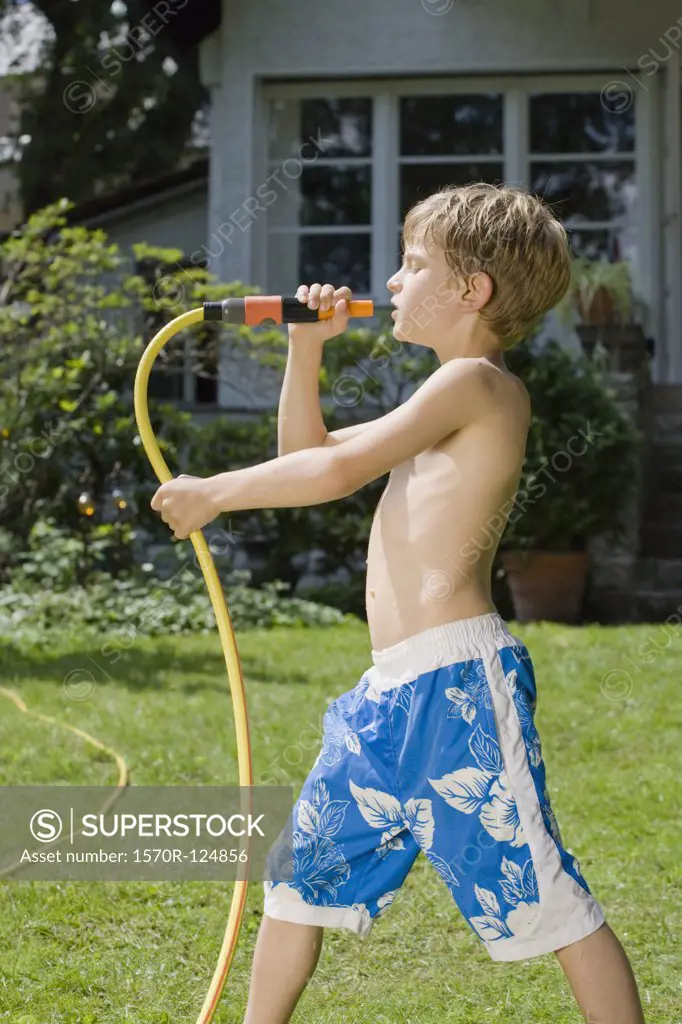 A young boy singing into the end of garden hose