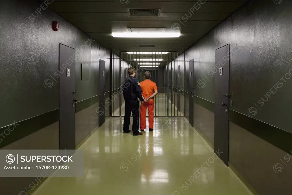 A prison guard leading a prisoner along a corridor